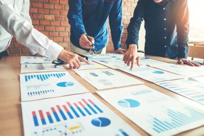 Three men reviewing business statistics charts doing a business evaluation